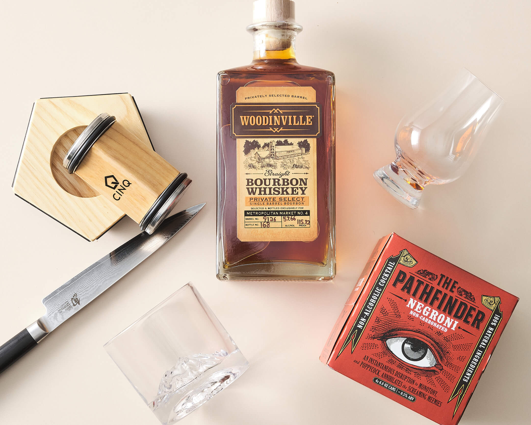 Knife sharpener, whiskey, whiskey glasses, and a red mocktail box