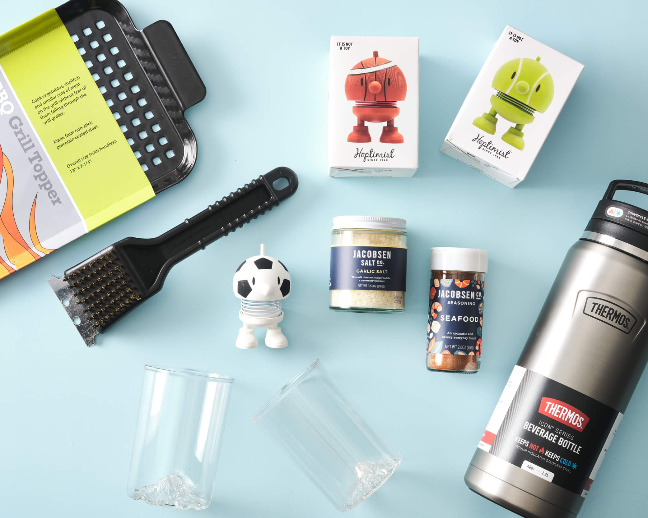 Grill tools, Hoptimist figurines, plastic cups, jarred salts, and a silver thermos