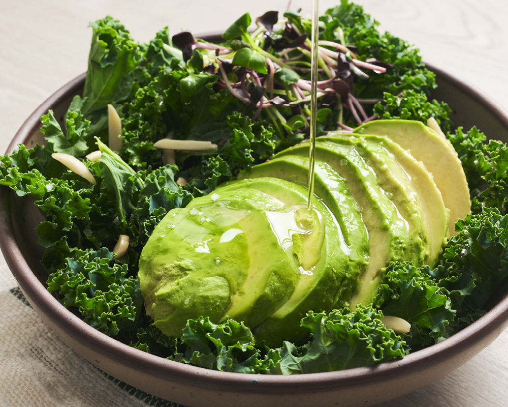 Salad with pour of avocado oil over avocado slices