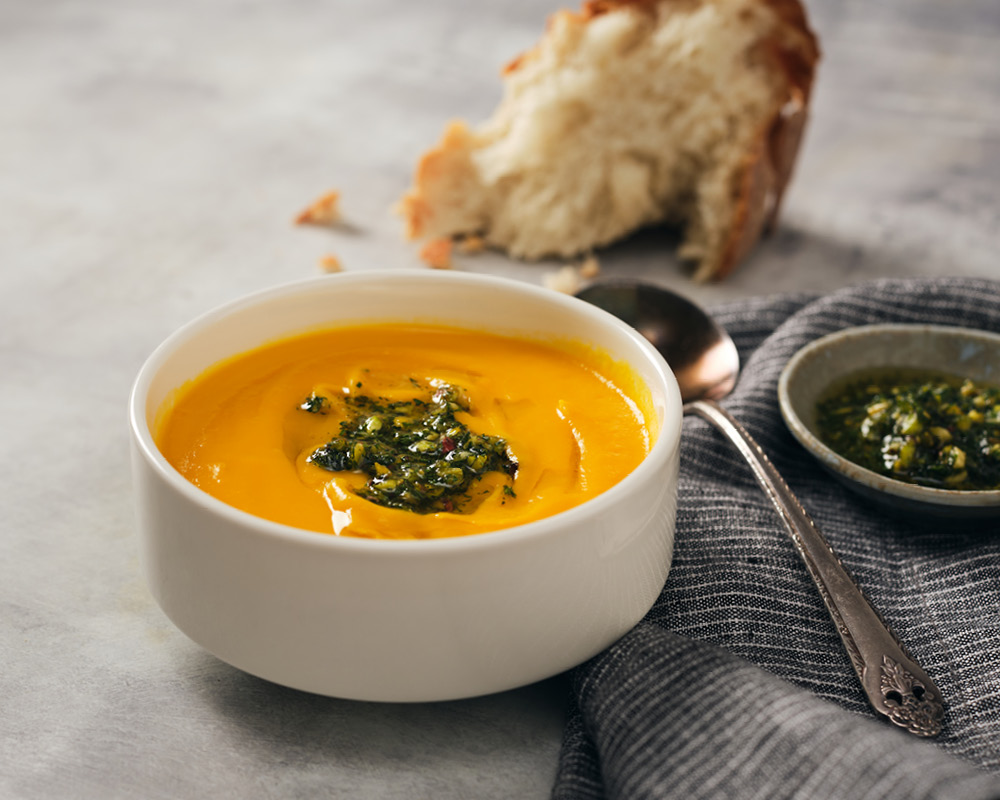 Carrot ginger soup with dollop of carrot top pesto and crusty bread