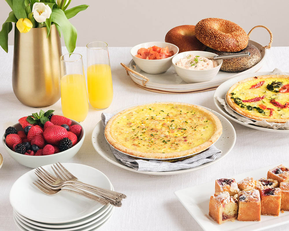 Image Alt Text A table set for brunch with quiche, bagels, fresh berries, flowers and juice