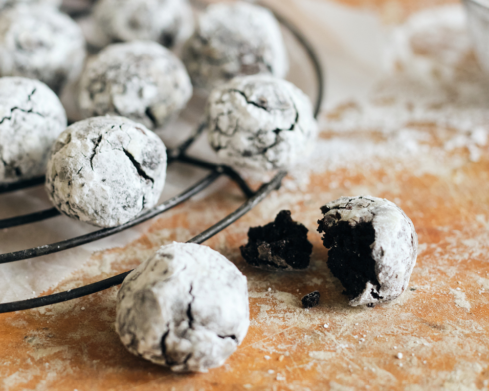 Chocolate crinkle cookies on cooling rack placed atop powdered surface