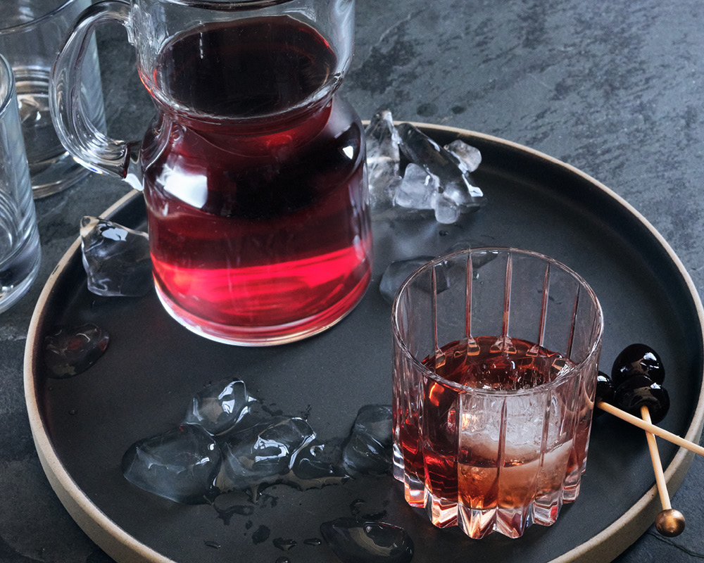 Pitcher and glass filled with The Big Apple on a black tray
