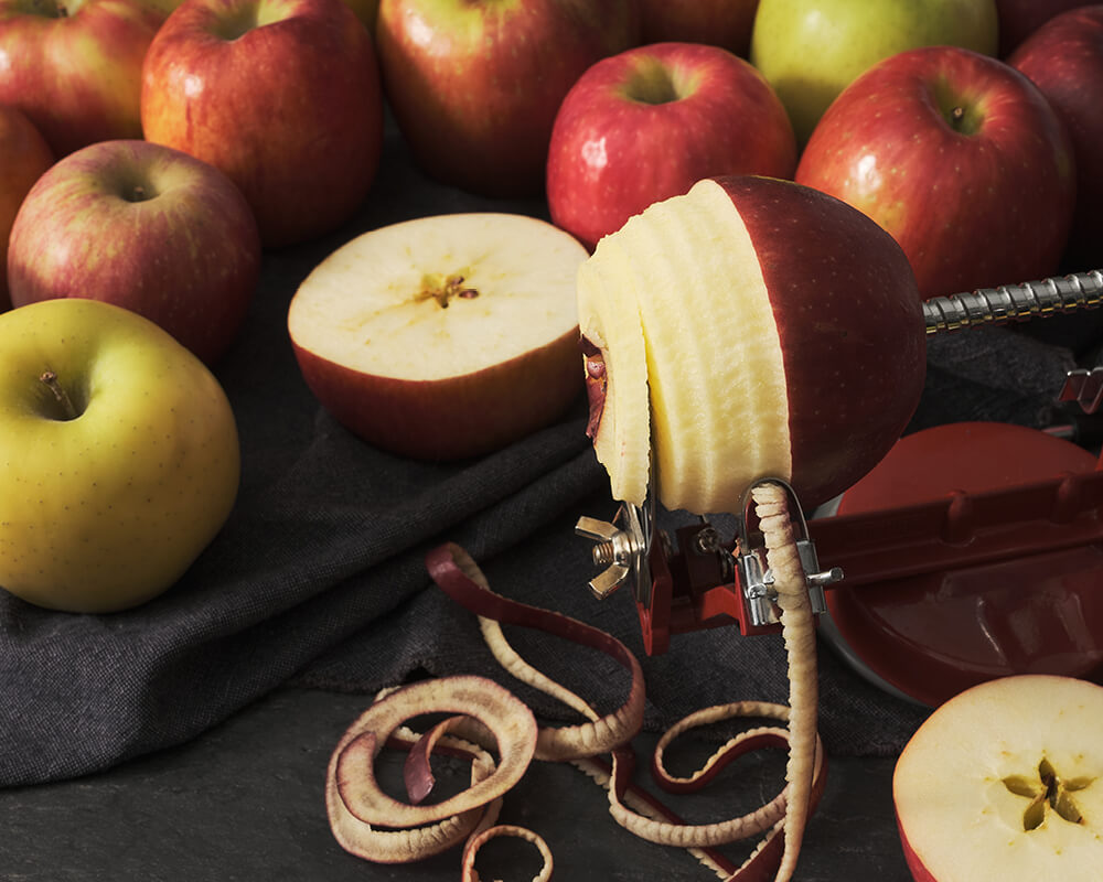 An apple cored and pared in ribbons on a black background