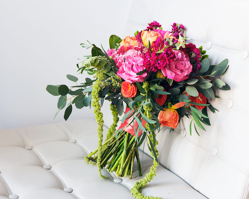 Green, pink, orange floral bouquet on a white chair