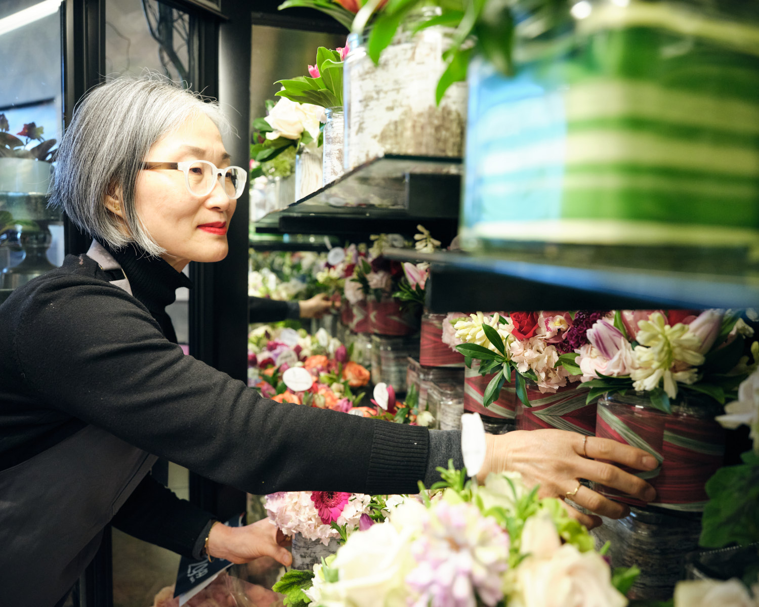 Yumi Han placing floral arrangements on a shelf