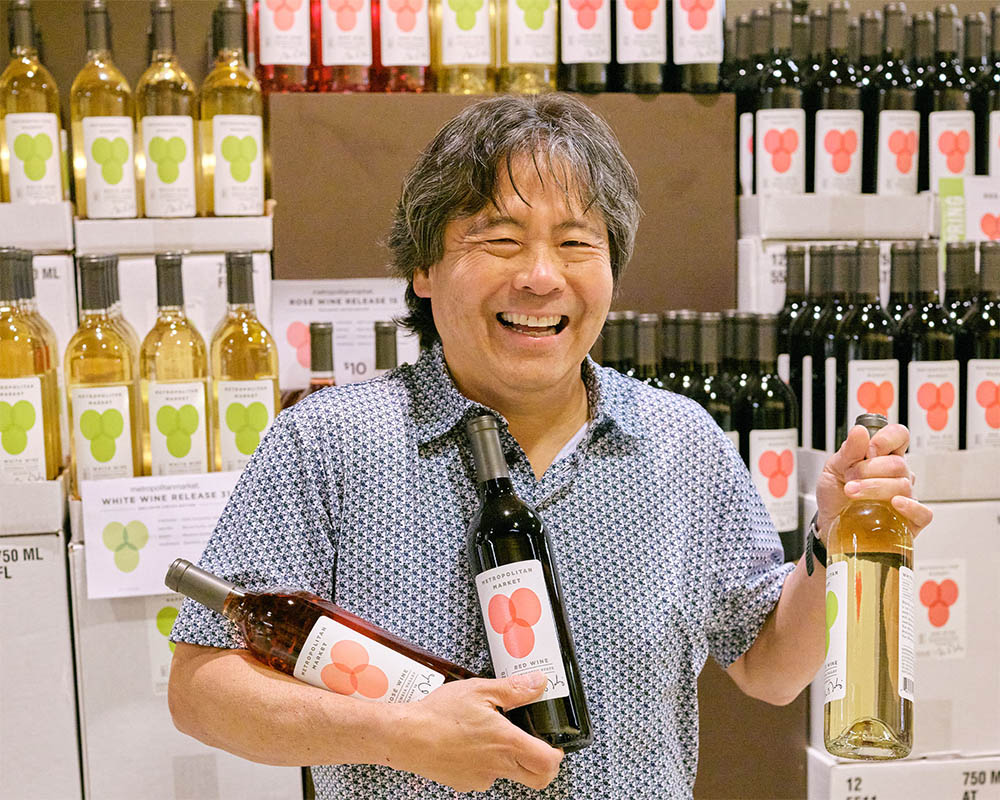 Mark Takagi holding three bottles of wine