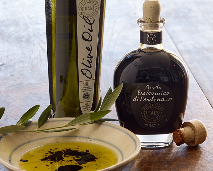 Bottles of balsamic vinegar and olive oil behind a dish for dipping.