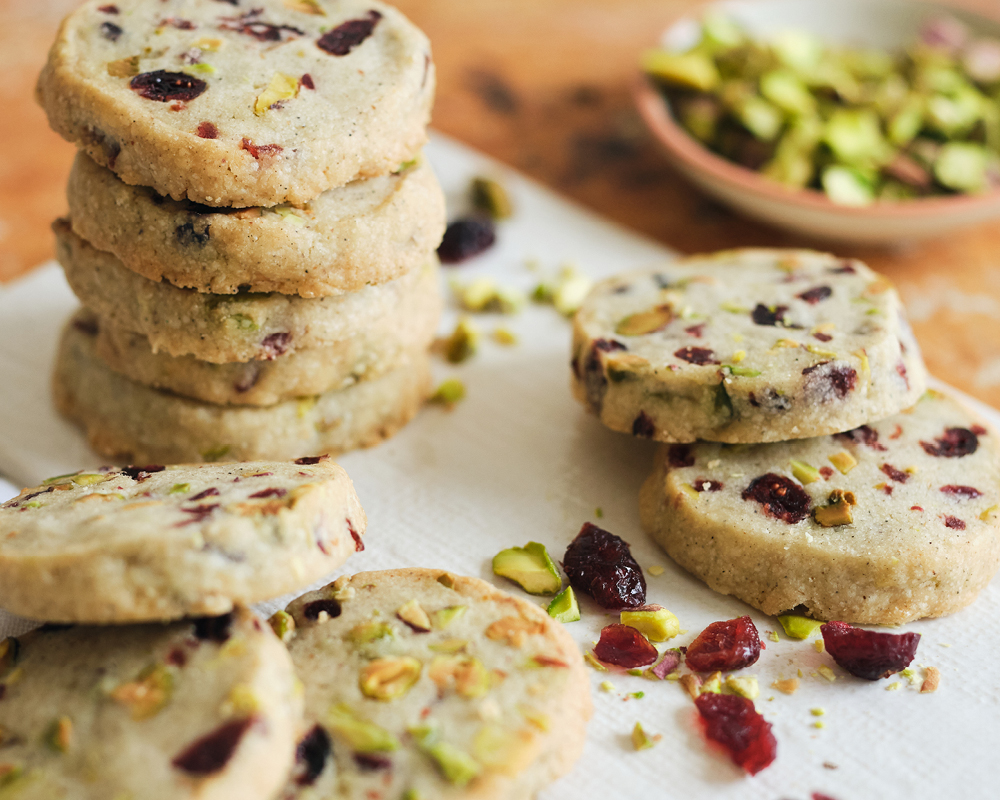 Cardamom Pistachio Cranberry Shortbread Cookies stacked on parchment paper