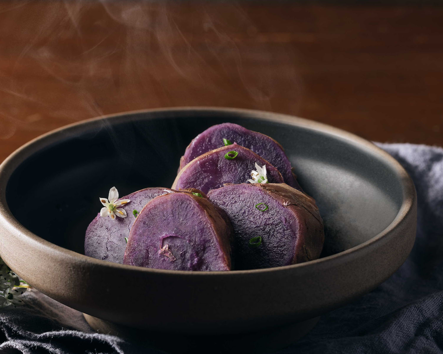 Sliced purple sweet potato topped with tiny white flowers.