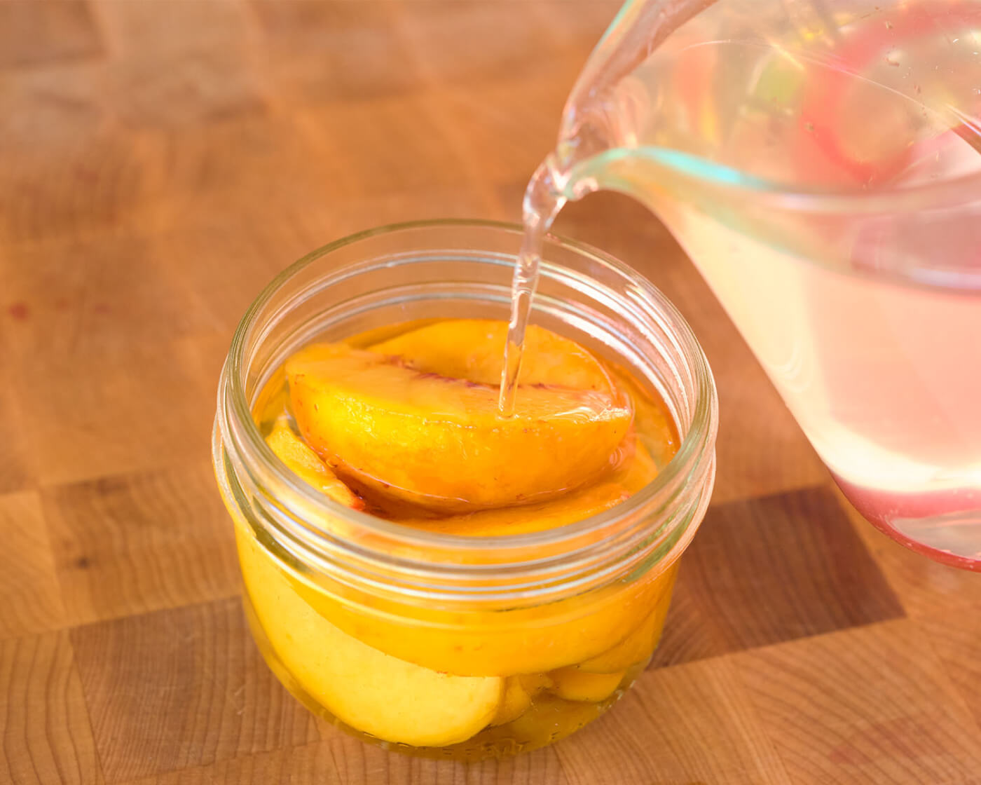 filling peach jar with syrup