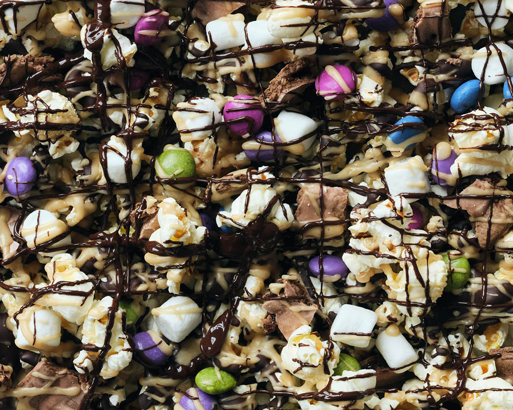 Popcorn with candy, marshmallows, and drizzled with chocolate.