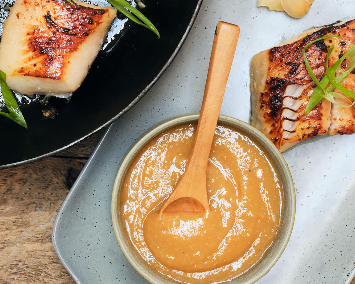Marinade in a bowl on a tray with cooked fish.