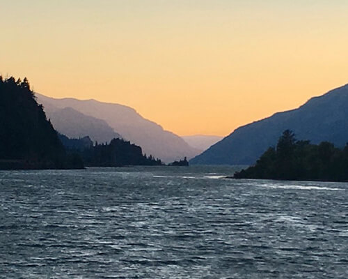 River at sunset with hills in the background.