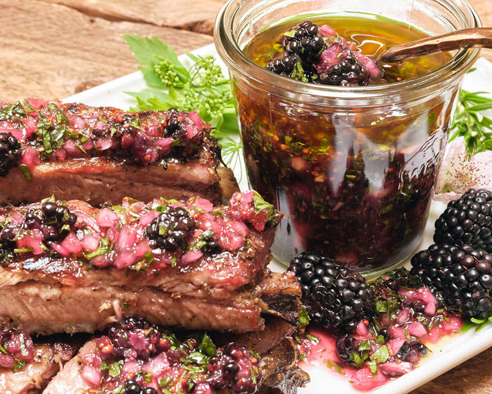 Ribs smothered in a sauce with fresh blackberries.