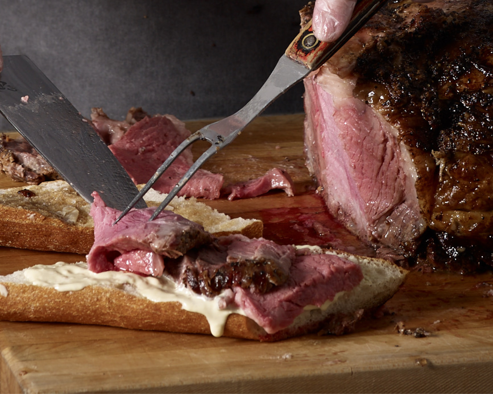 Chef slicing prime rib onto a sandwich.