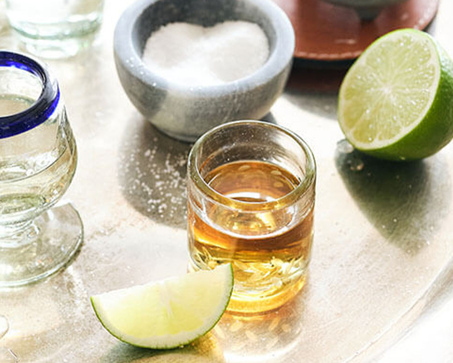 shot glass of tequila with limes and salt