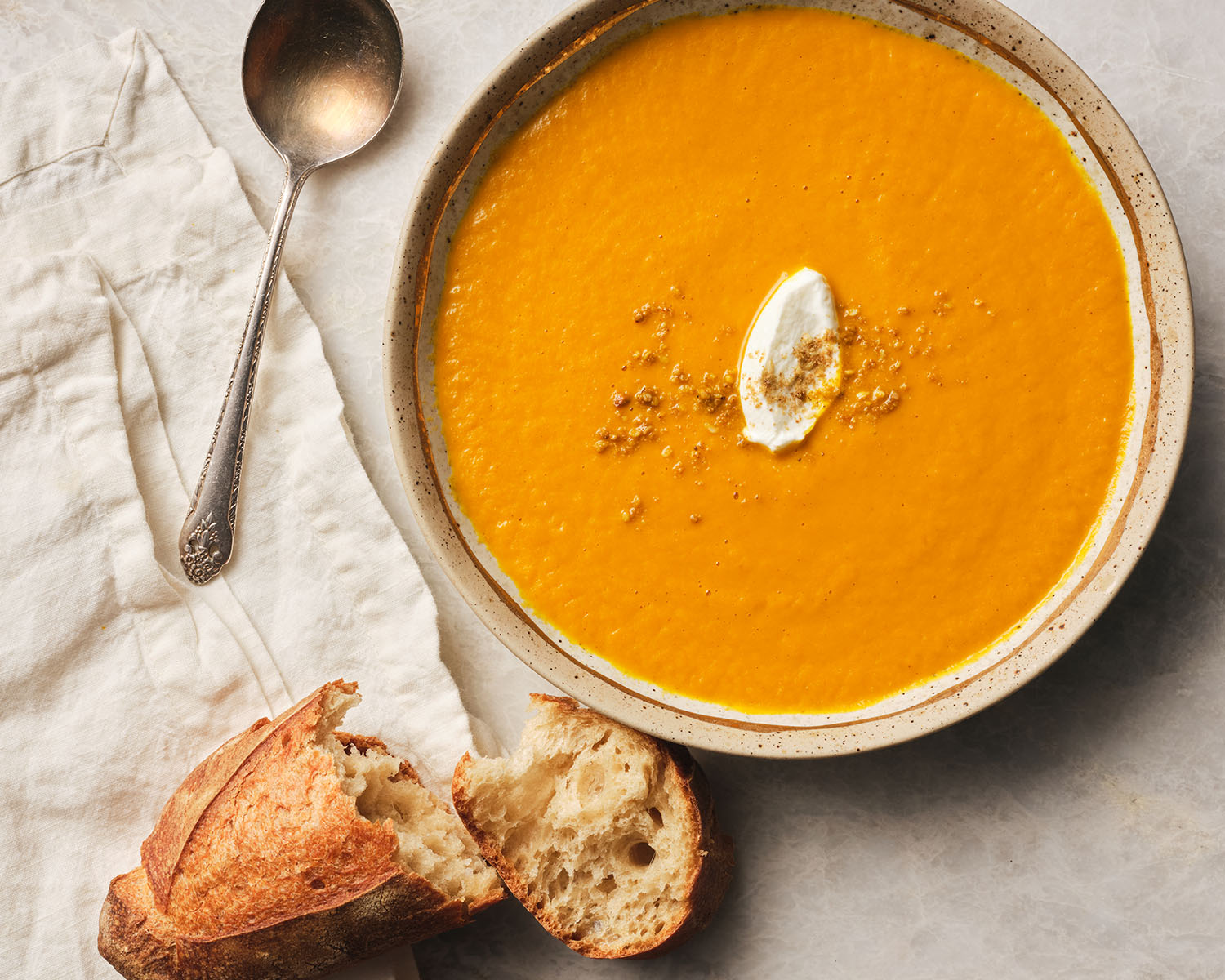 Orange soup topped with a dollop of cream and served with crusty bread.