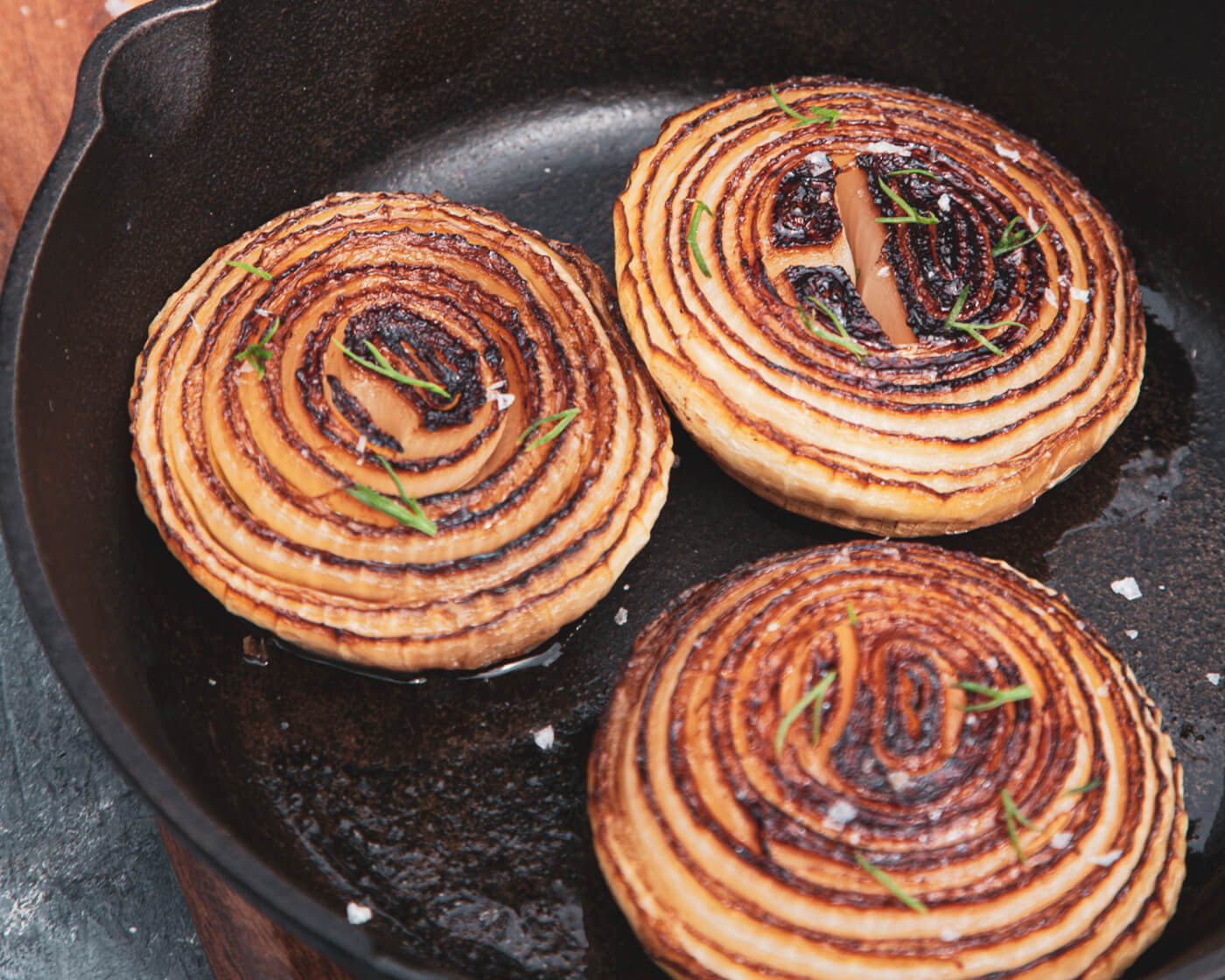 three onion slabs frying in a pan