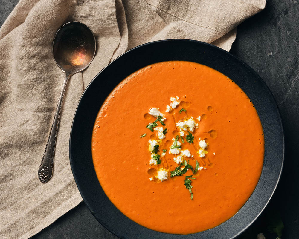 Red soup topped with cheese crumbles and herbs.