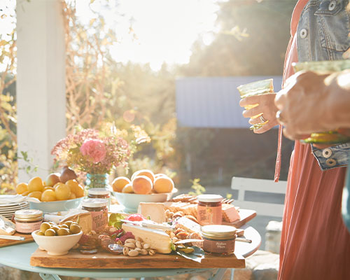 Table filled with cheese trays, preserves, and fresh fruit.