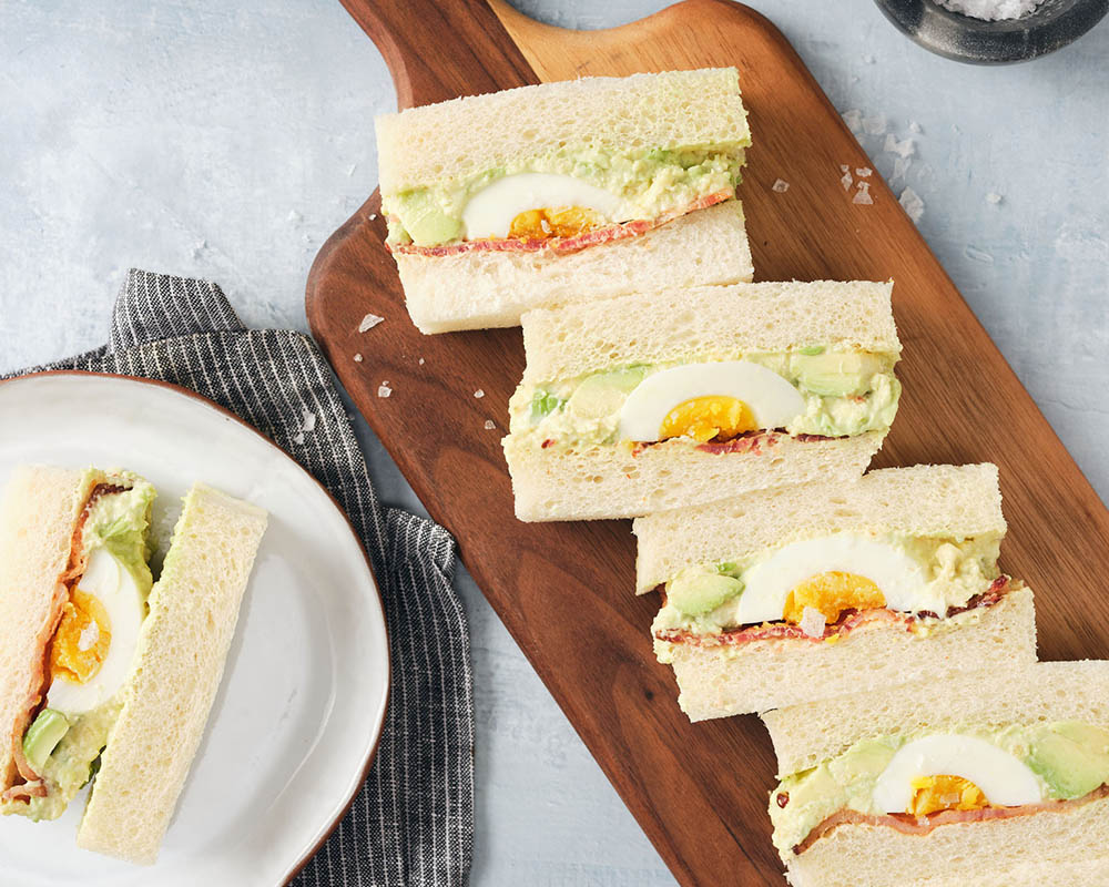 bacon and egg sandwiches on a plate and cutting board