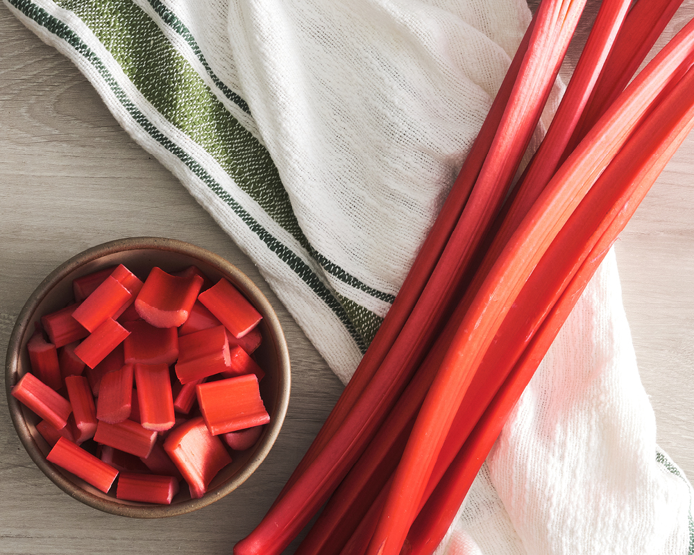 Rhubarb stalks on napkin with chopped pieces in bowl