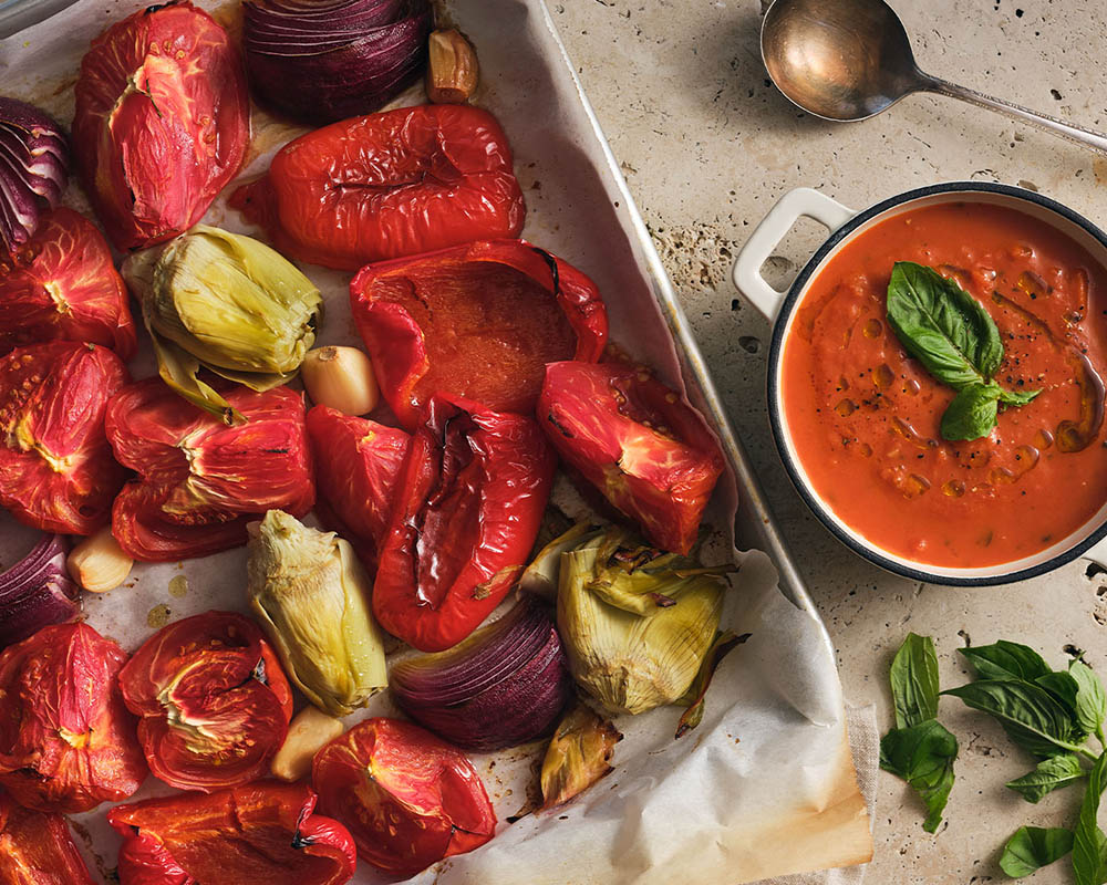 Roasted vegetables on a sheet pan and a bowl of soup