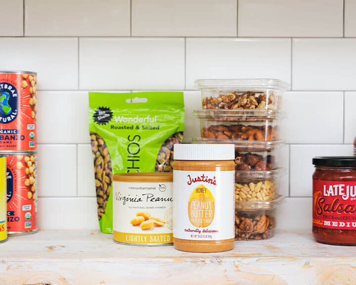 Packages of nuts and peanut butter on a pantry shelf.