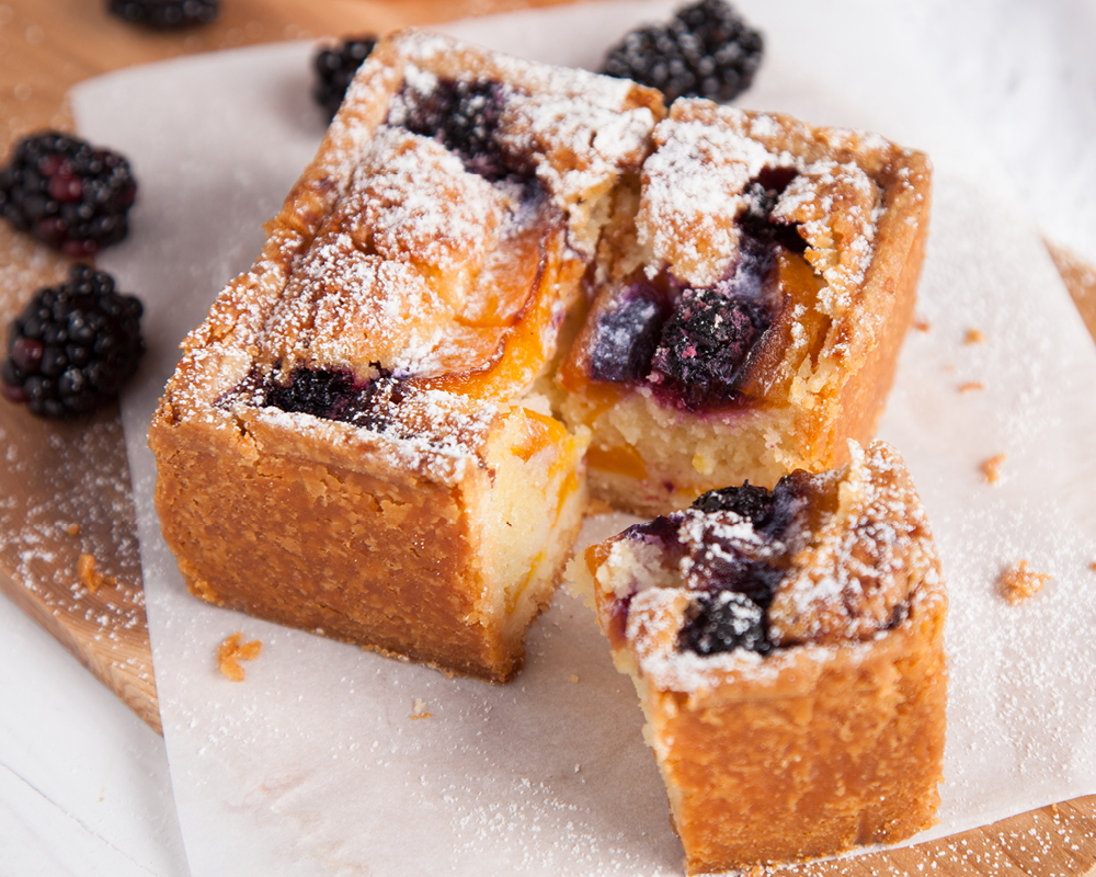 Bakewell Tart with a corner cut off surrounded by blackberries
