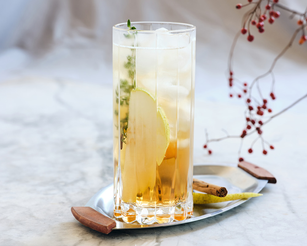 Pear Spritz cocktail on a silver platter with decorative berries
