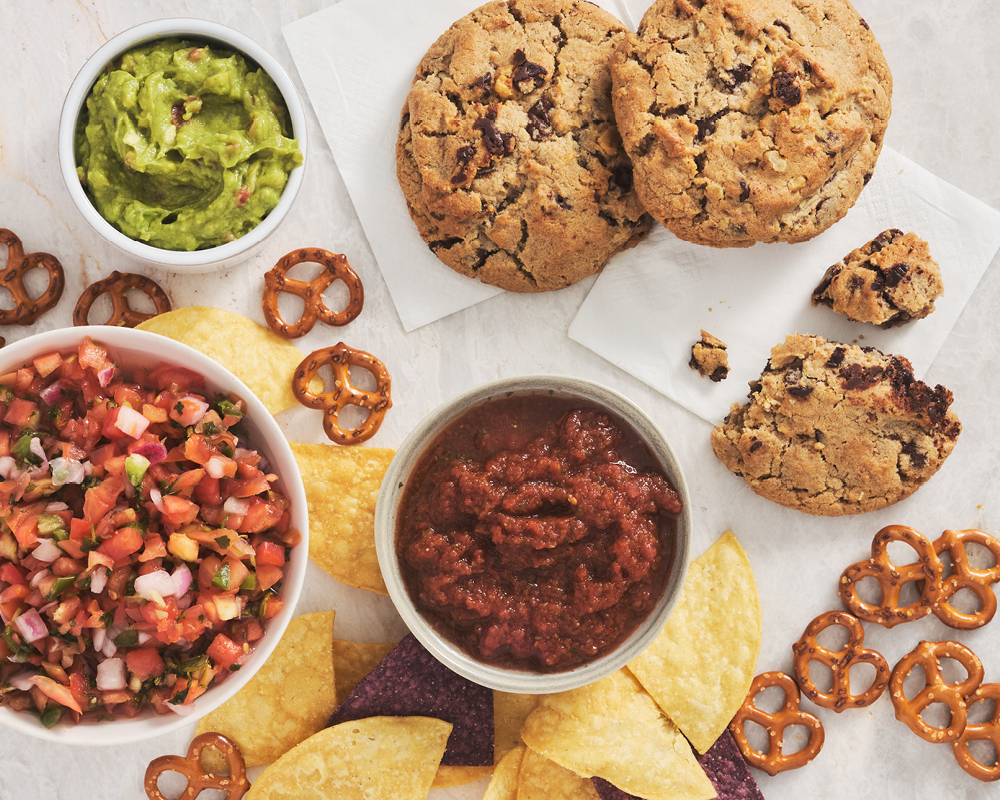 Salsa, guacamole, chips, pretzels, and chocolate chip cookies