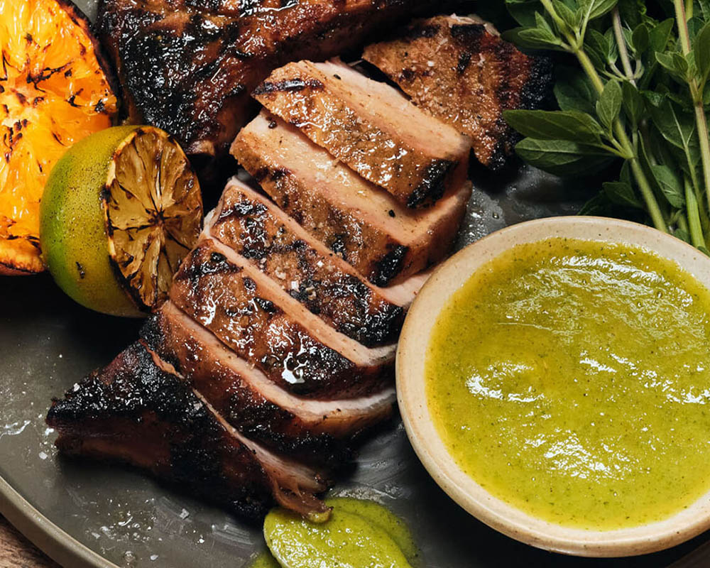 Sliced meat and small bowl of bright green marinade.