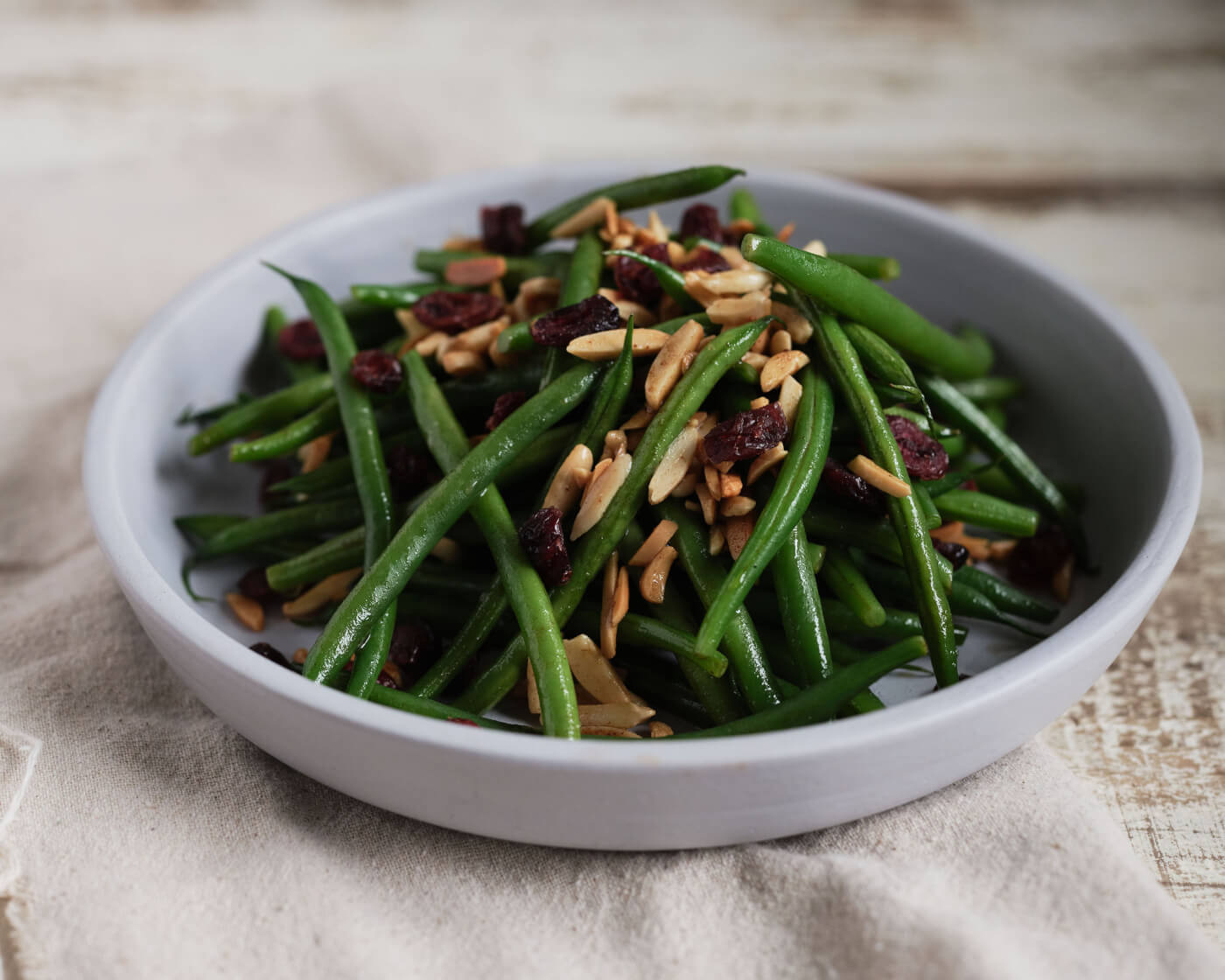 Bowl of green beans with slivered almonds and dried cranberries