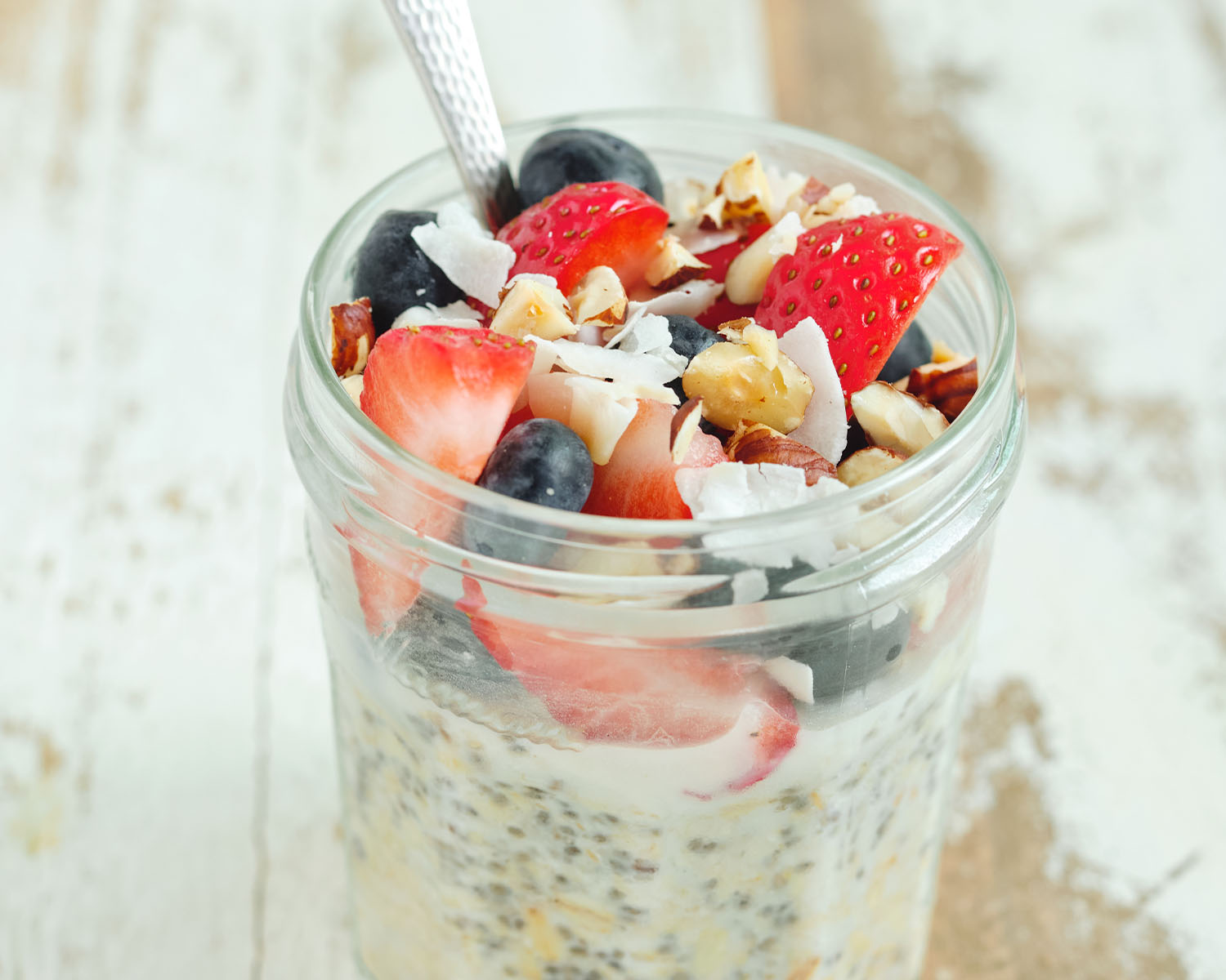 Oat and chia seed pudding in a jar topped with fresh fruit.