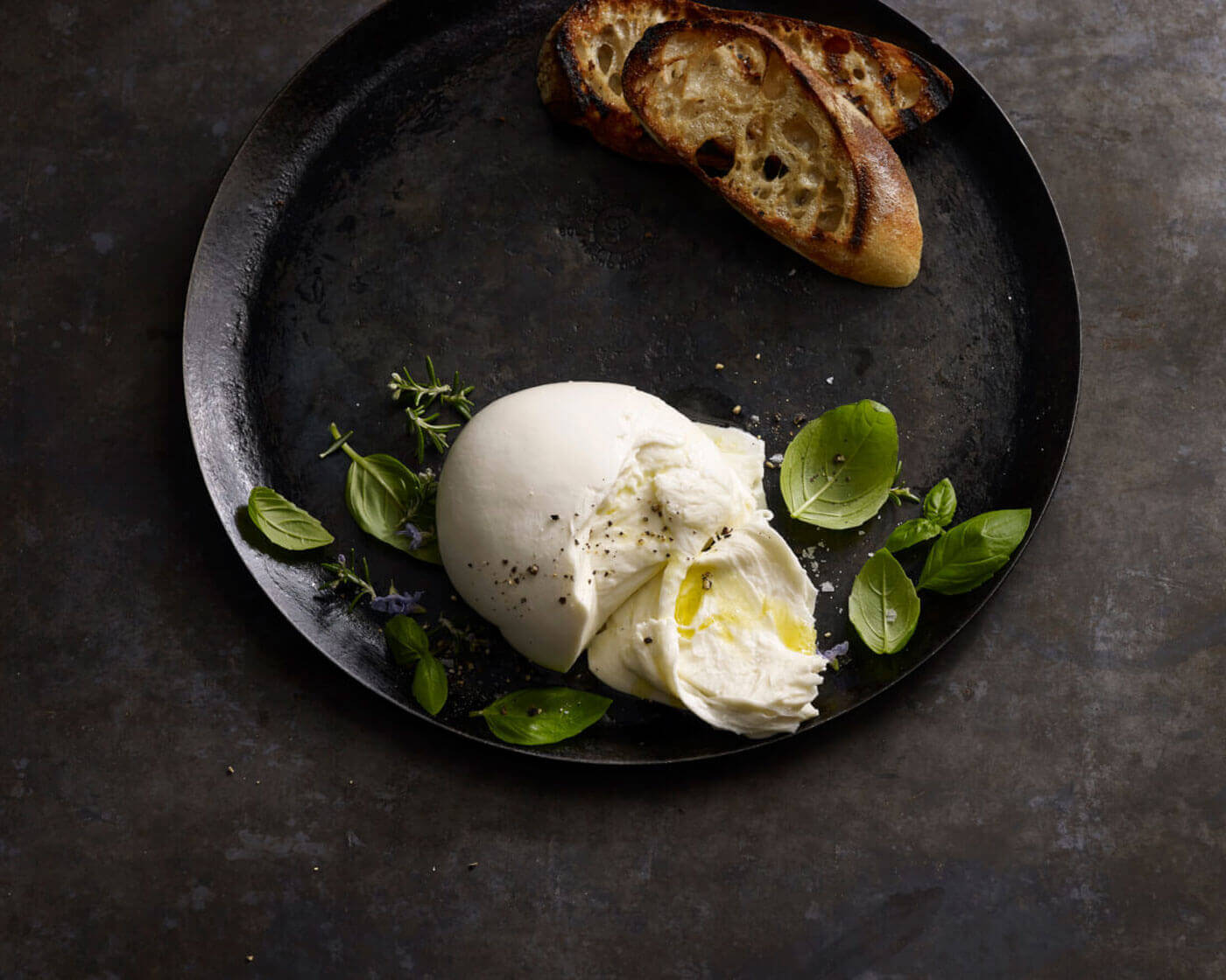 Fresh mozzarella on a plate with basil and toasted baguette slices