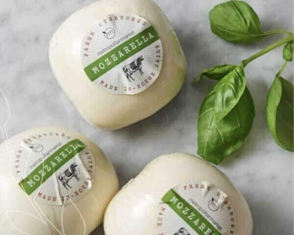 Three round packages of Metropolitan Market mozzarella with basil leaves.