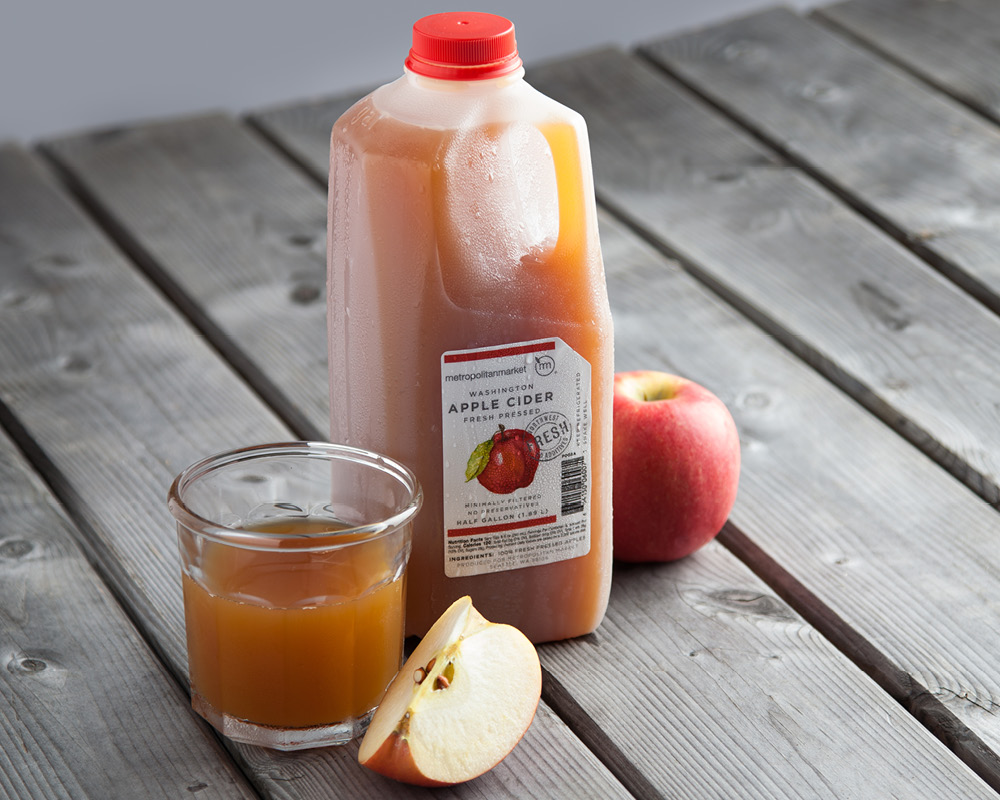 Jug of apple cider with filled glass and apples