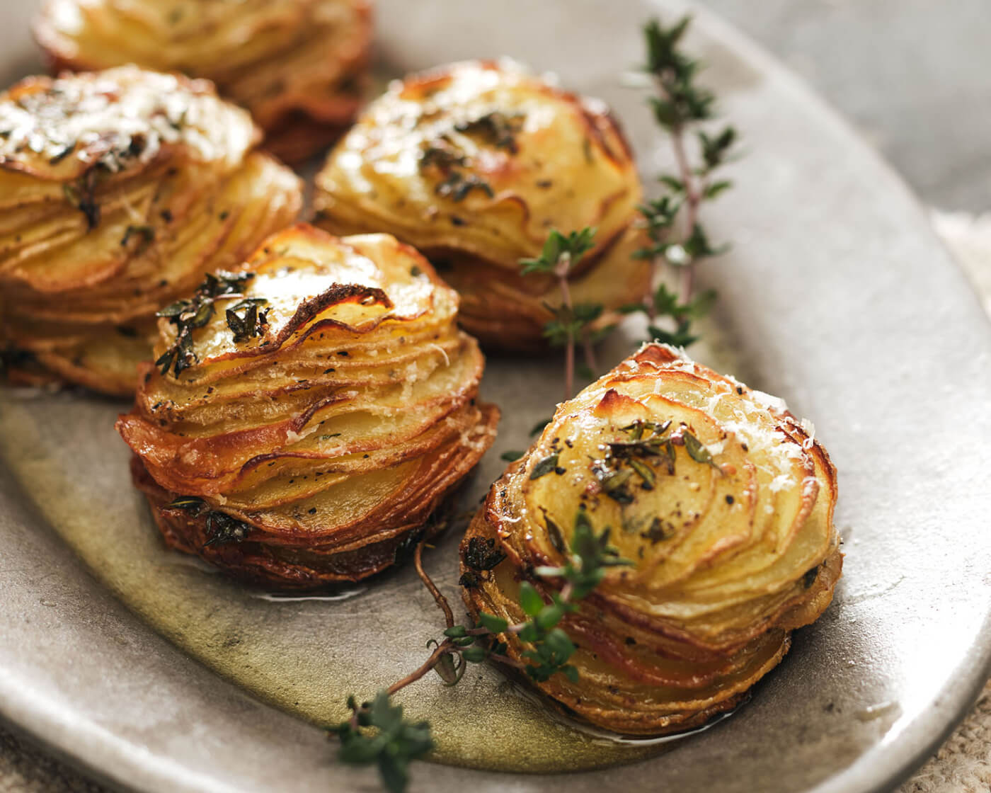 Stacks of roasted, crispy, thinly sliced, potatoes on a silver plate.