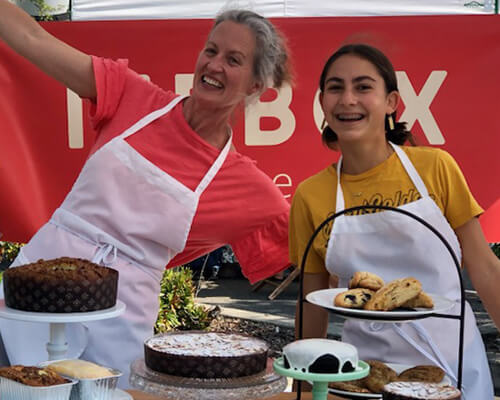 Lindsay Gott and friend smiling behind a display of baked goods.