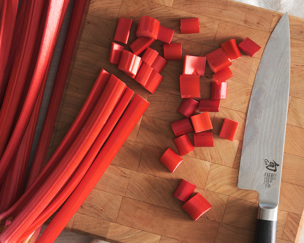 Rhubarb on chopping block with chopped pieces and knife