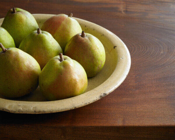 Ripe pears in a bowl on a wooden table.