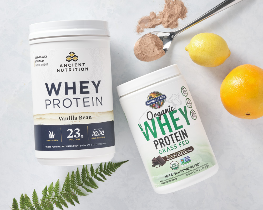 Two containers of whey protein styled with citrus and a fern