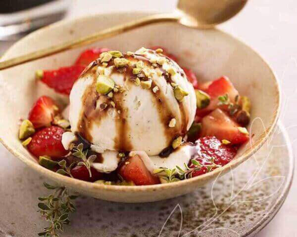 Ice cream topped with balsamic vinegar, strawberries, and nuts.