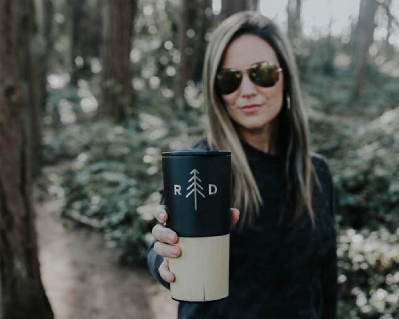 Anne Farrens holding a hot beverage tumbler with Retreat Drinks logo