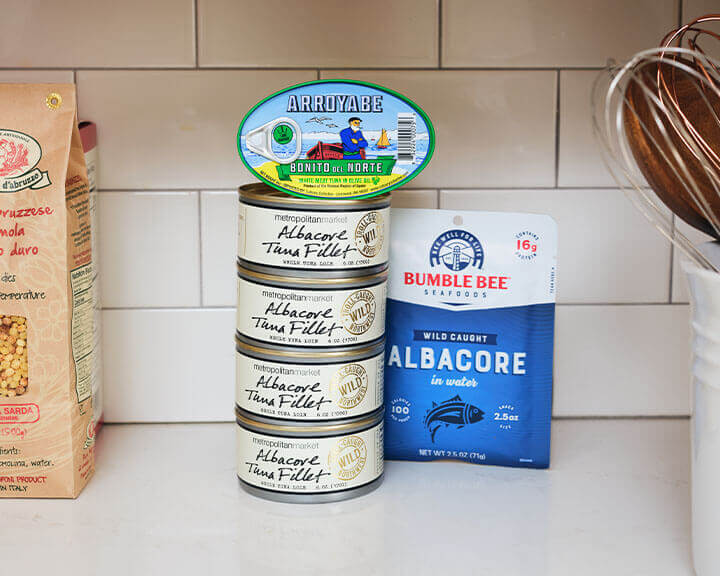 Packages of tuna on a pantry shelf.