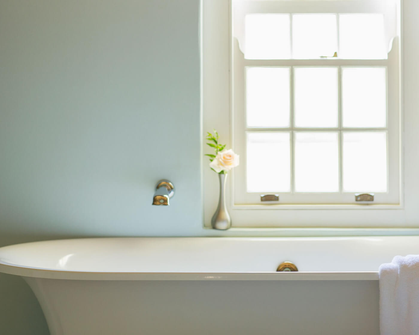 A bathtub with a vase and flower, calming colors