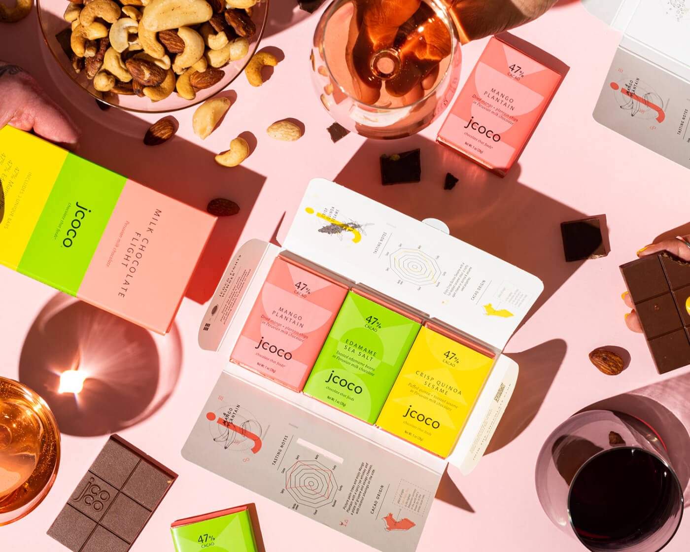 jcoco chocolate bars with nuts, whiskey on a pink background flatlay photography