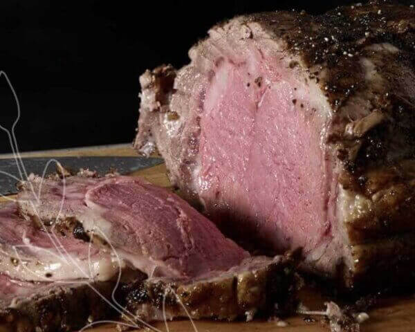 Close up image of a prime rib roast with slices on one end.