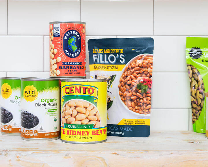 Packages of different kinds of beans on a pantry shelf.